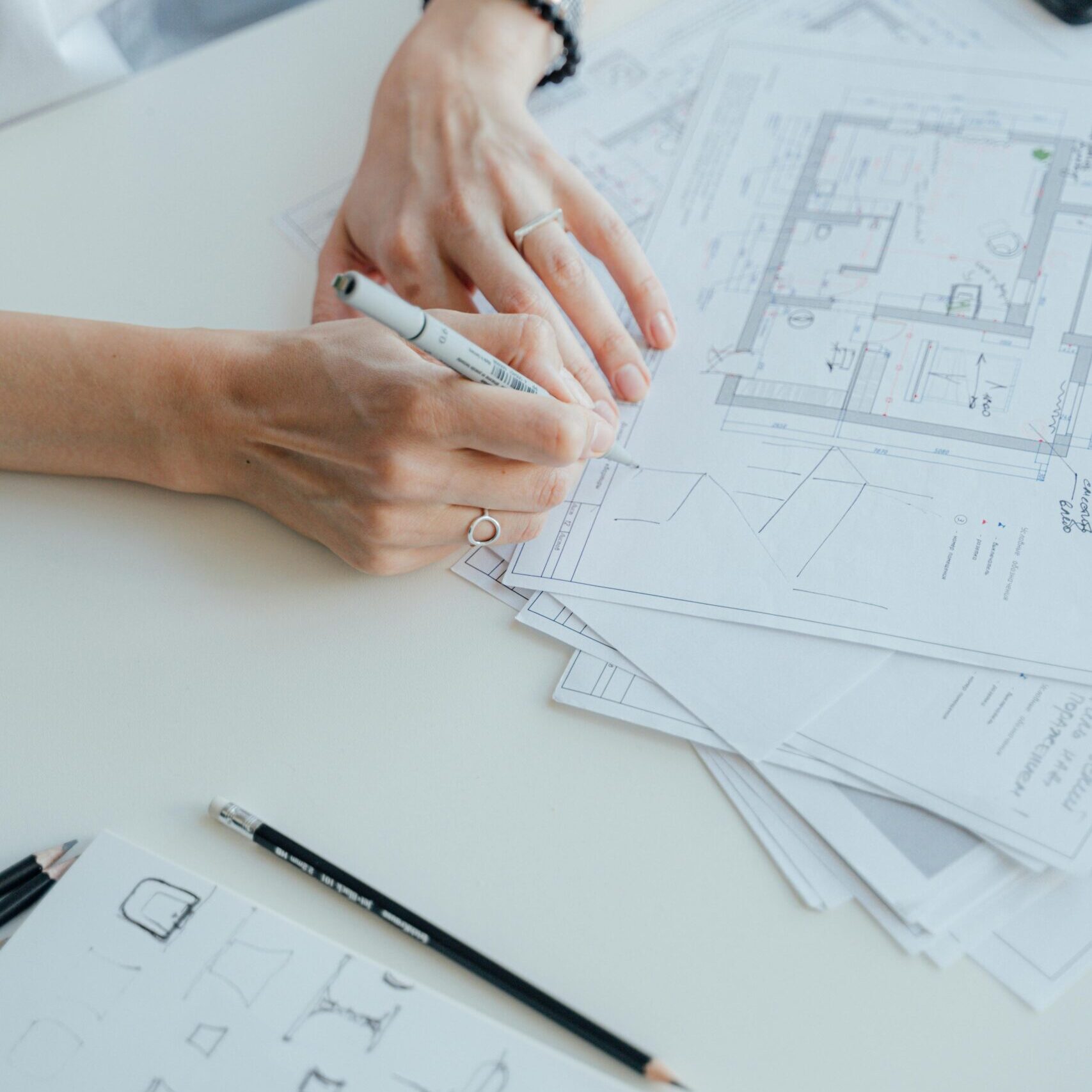 An architect writes notes on design plans while sitting at a desk, focusing on details.